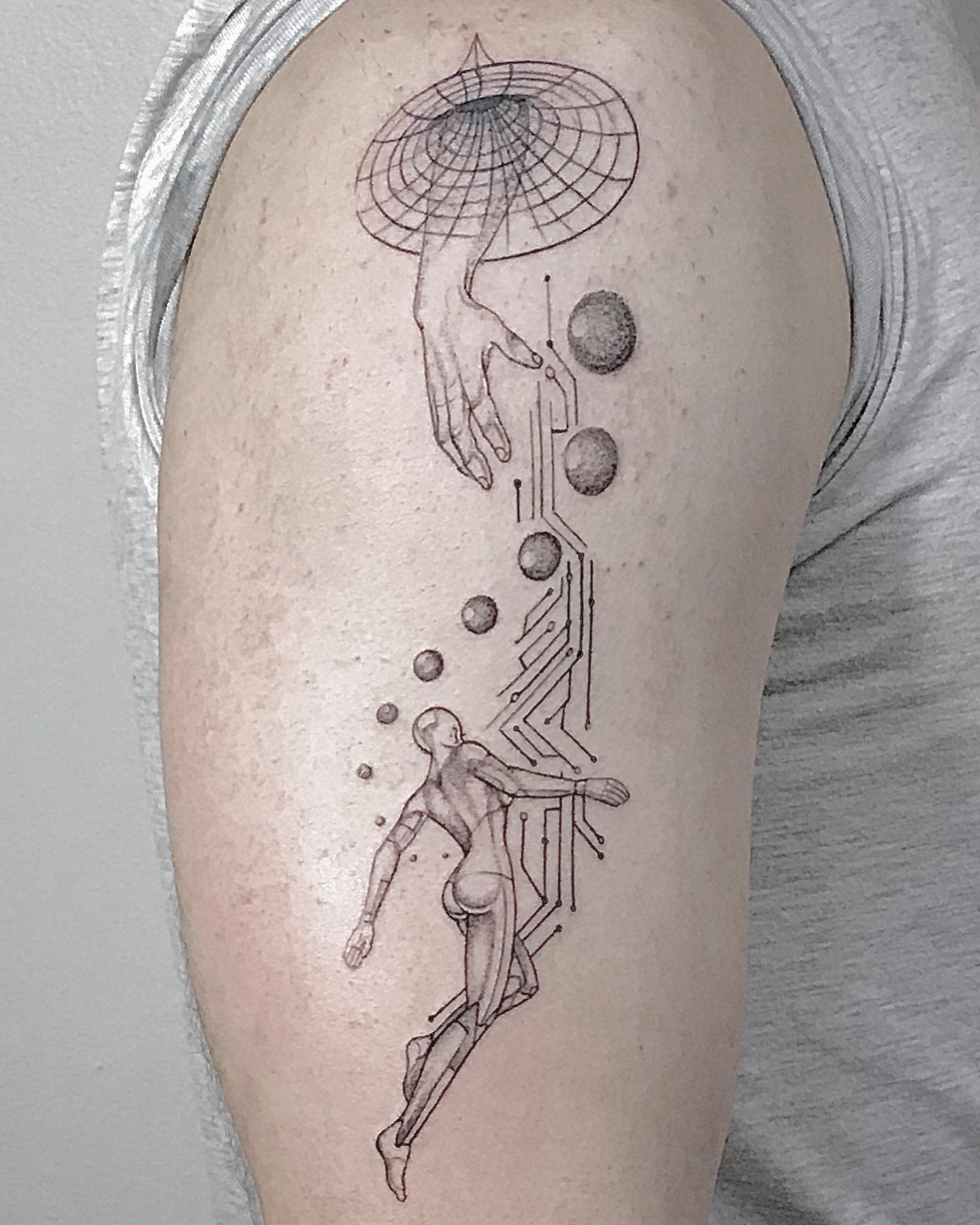 A tattoo featuring a cyborg reaching towards a circuit hand emerging from a futuristic grid